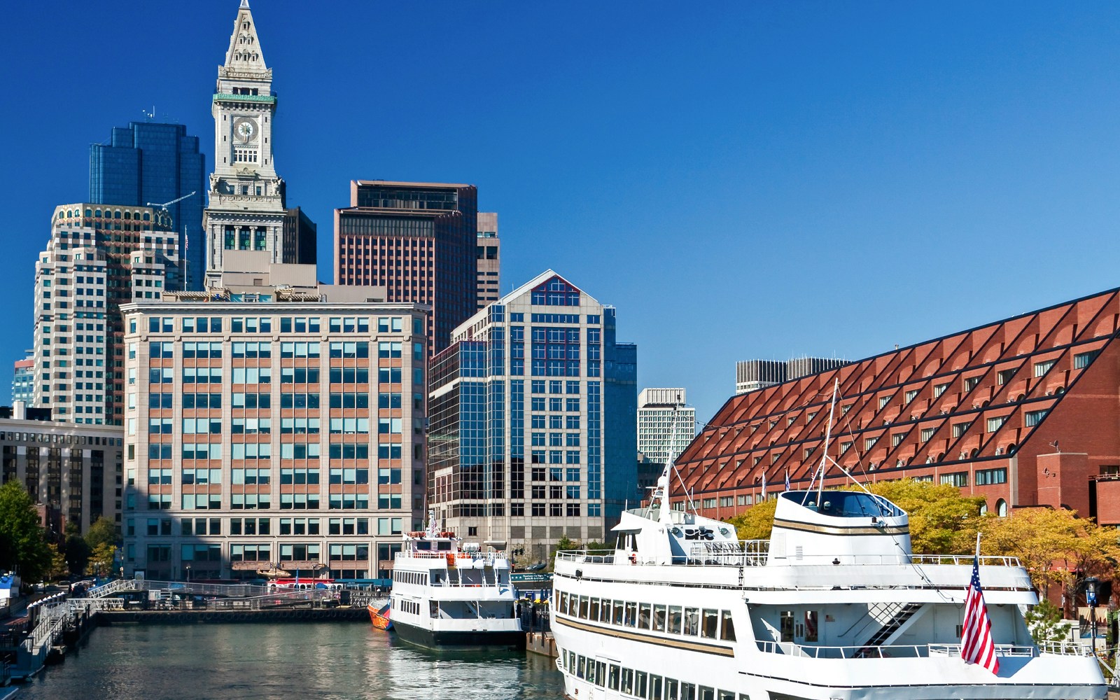 Boston Harbor cruise ships docked at Long Wharf with city skyline in the background.