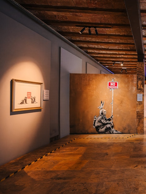 Tourists walking through Banksy Museum in Barcelona, viewing street art exhibits.