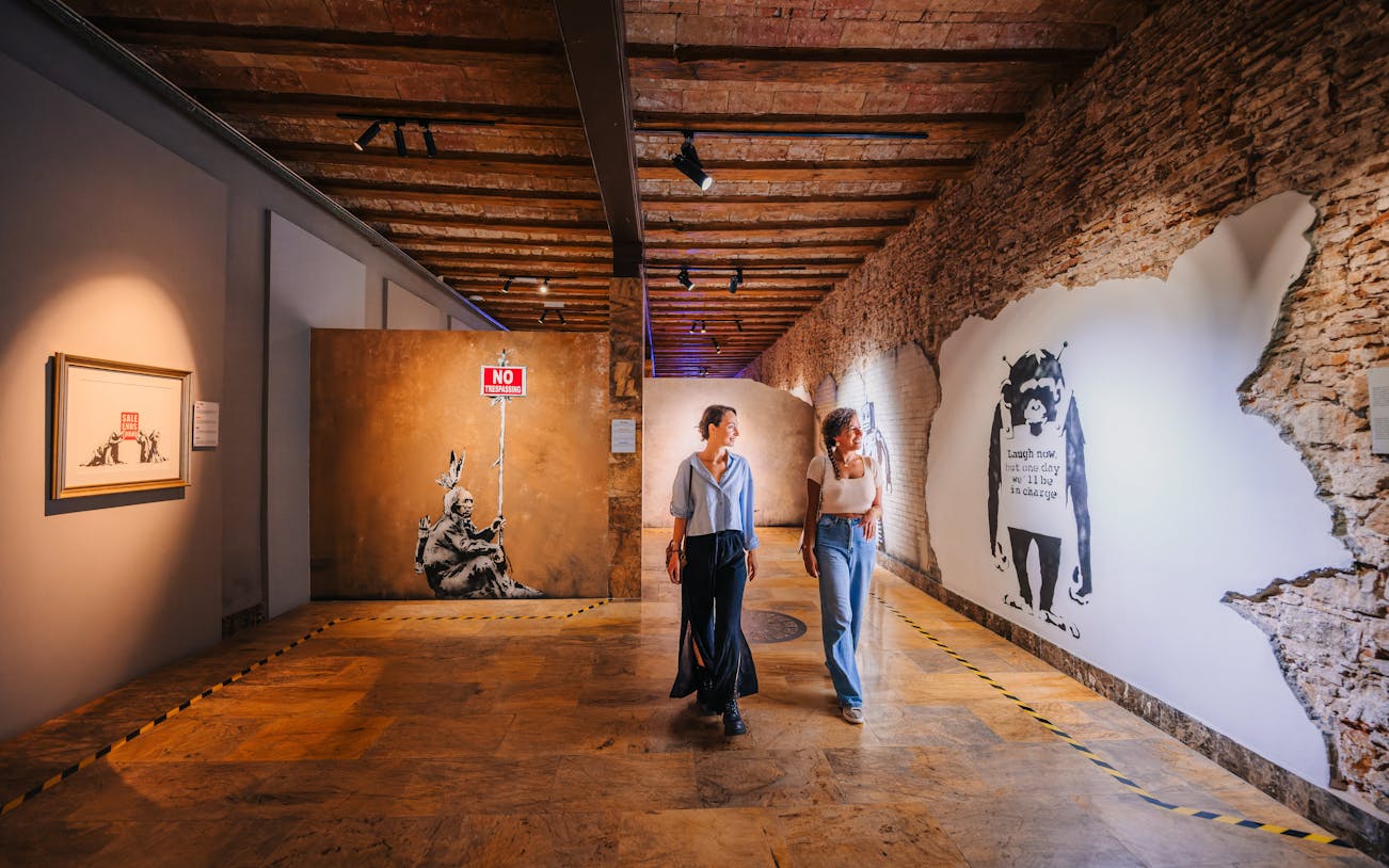 Tourists walking through Banksy Museum in Barcelona, viewing street art exhibits.