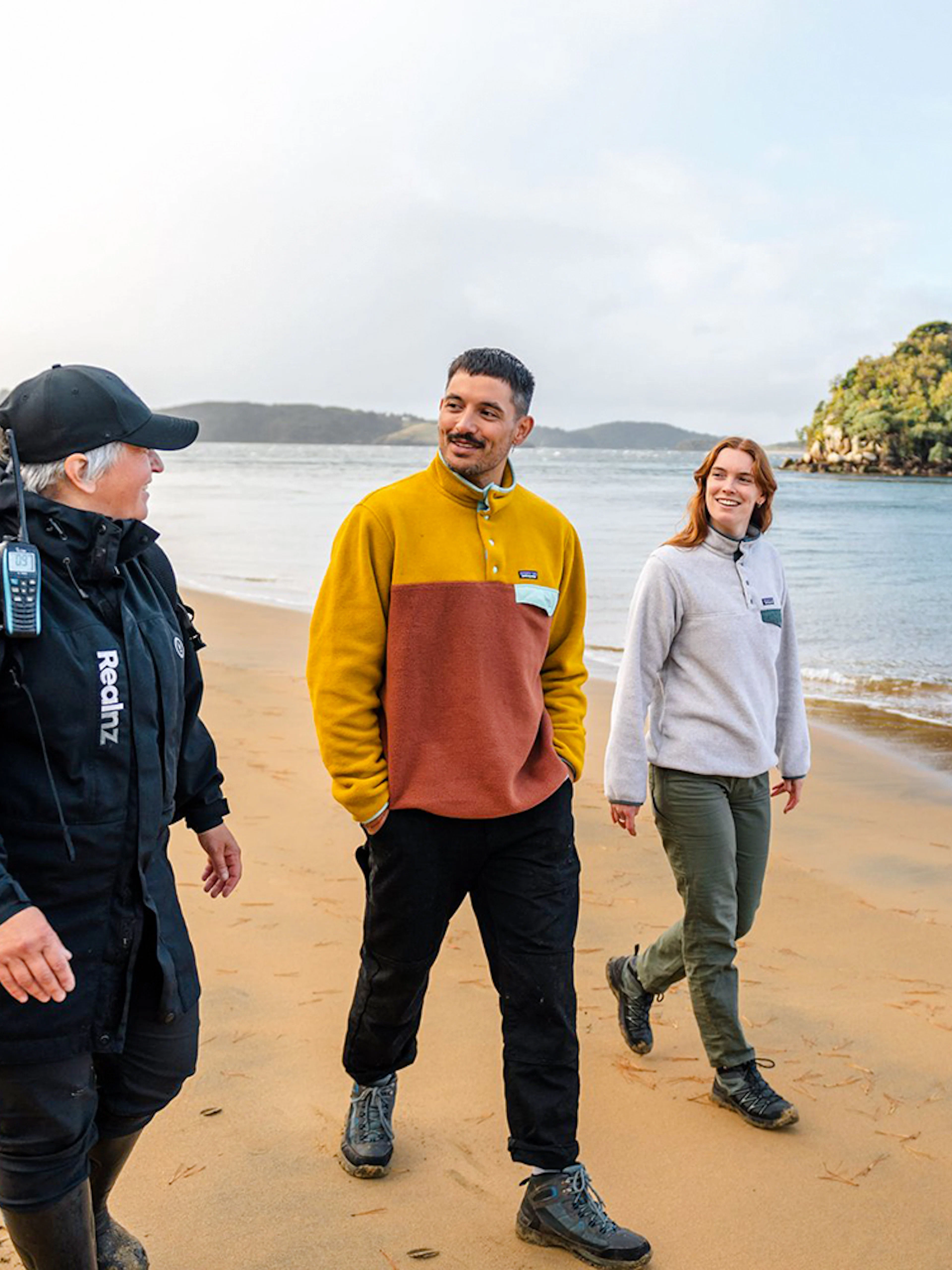 Guided group walking on Stewart Island beach during wilderness tour.