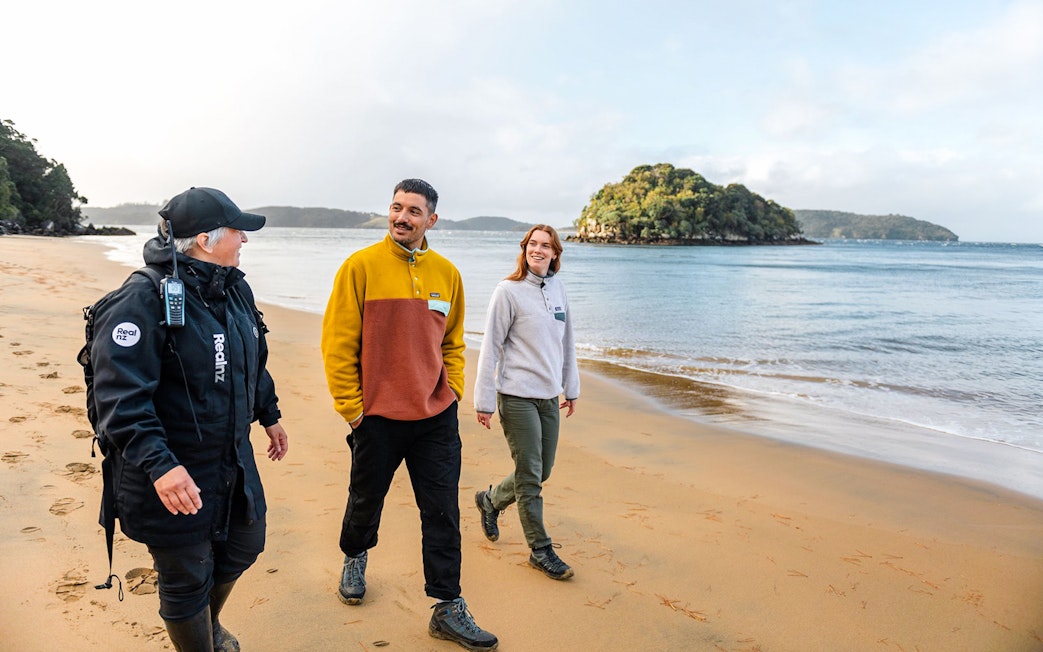 Guided group walking on Stewart Island beach during wilderness tour.