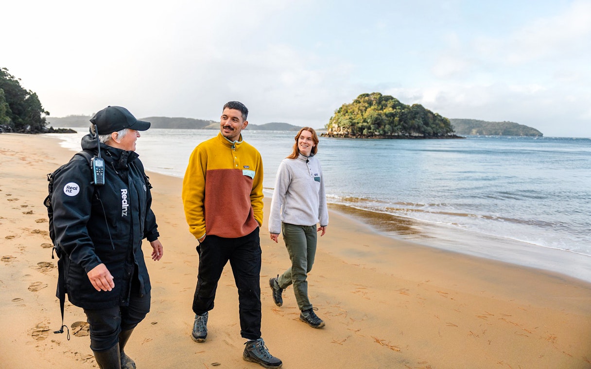 Guided group walking on Stewart Island beach during wilderness tour.