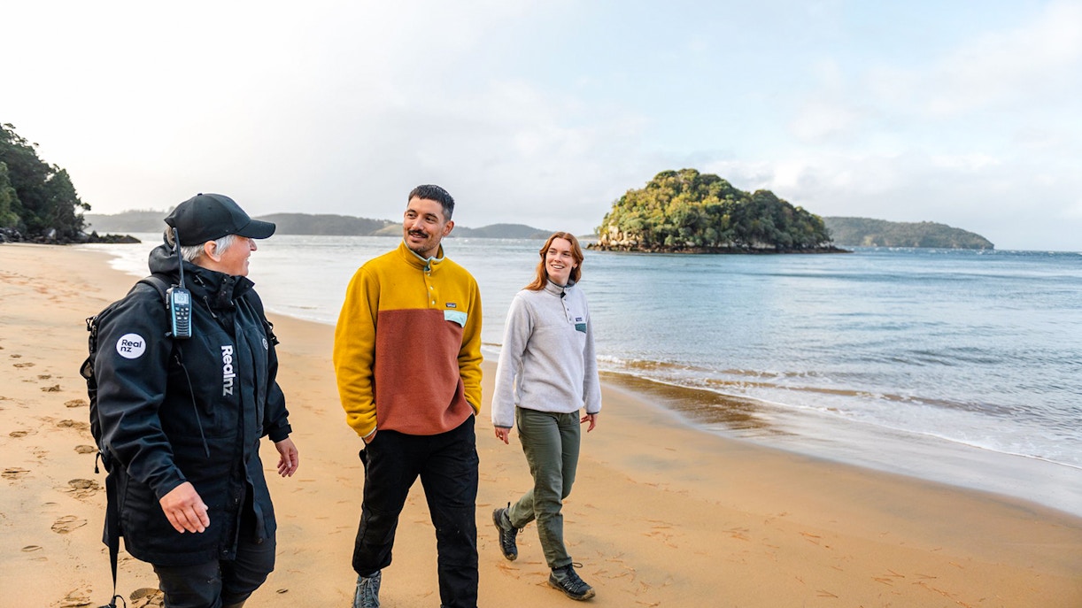Guided group walking on Stewart Island beach during wilderness tour.