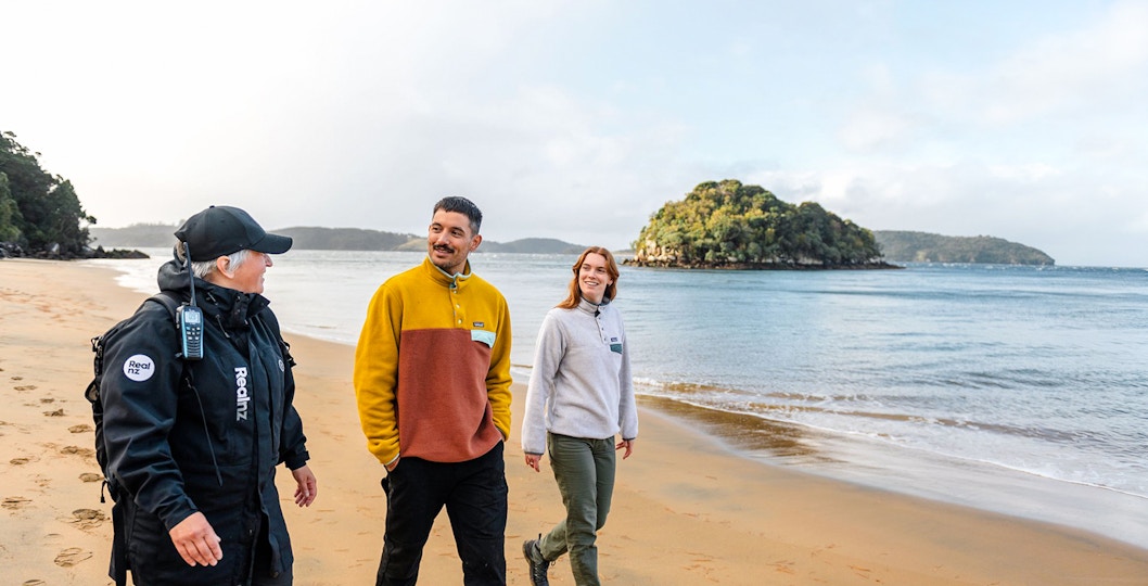 Guided group walking on Stewart Island beach during wilderness tour.