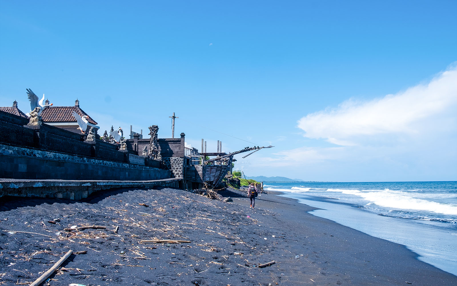 Kusamba Harbor black sand beach with traditional Balinese architecture and ocean view.