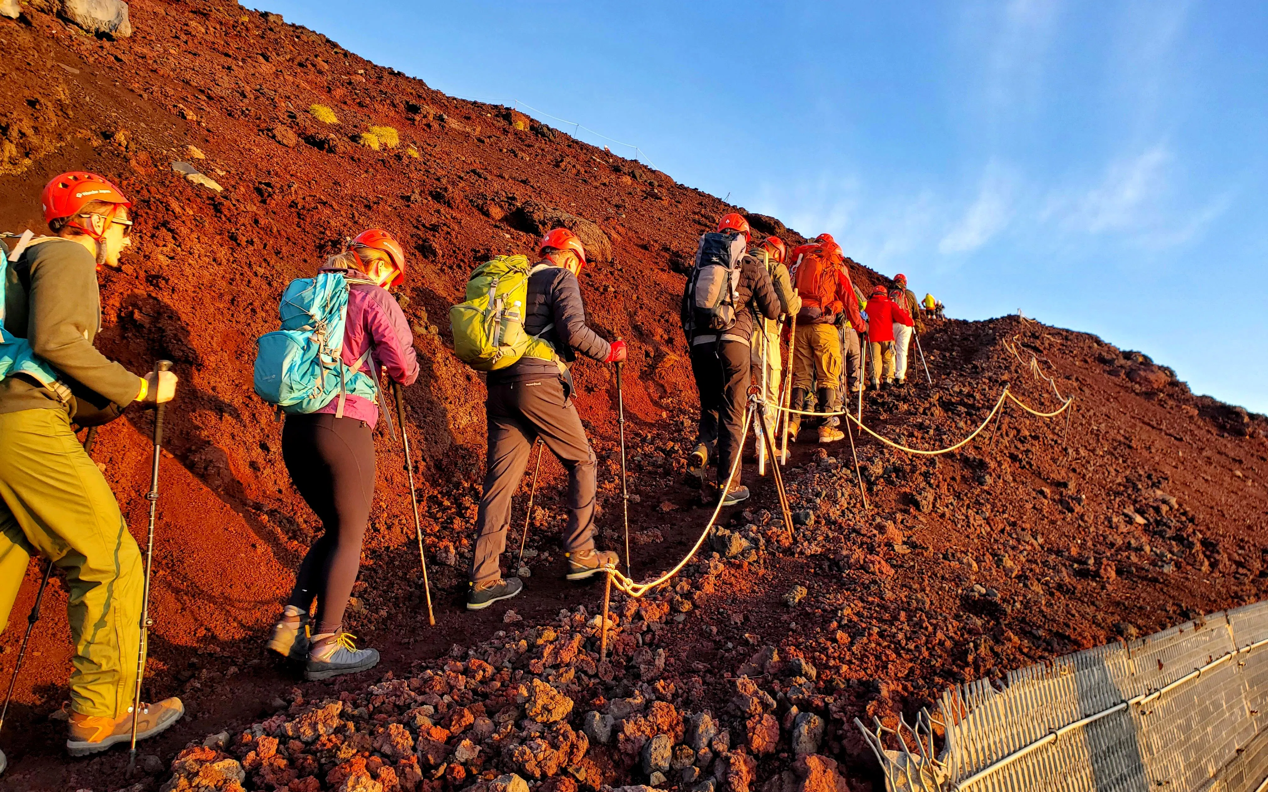 Climbers ascending rocky trail on Mt. Fuji during guided tour.