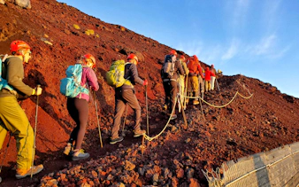 Climbers ascending rocky trail on Mt. Fuji during guided tour.