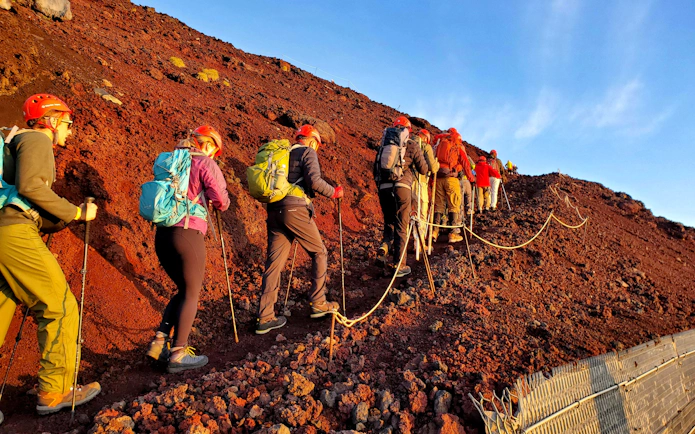 Climbers ascending rocky trail on Mt. Fuji during guided tour.