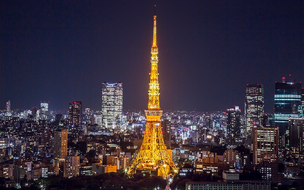 Tokyo Tower illuminated at night with city skyline in the background.