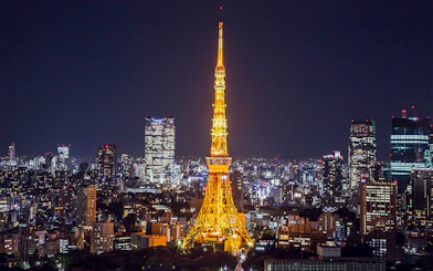 Tokyo Tower illuminated at night with city skyline in the background.