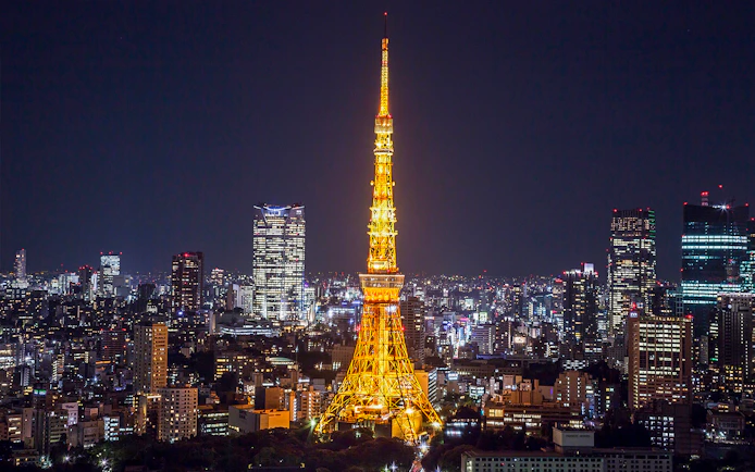 Tokyo Tower illuminated at night with city skyline in the background.