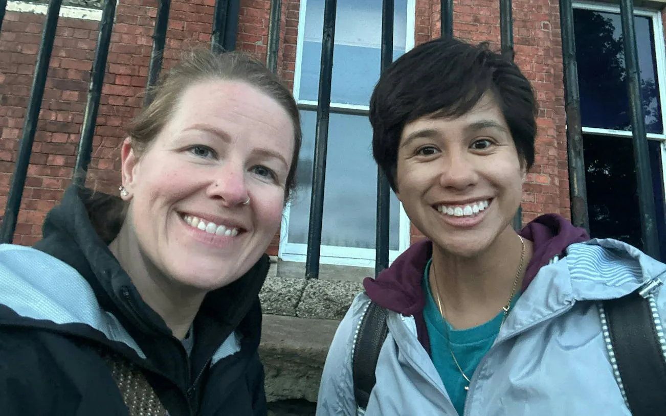 Two people smiling in front of a historic brick building in Belfast.