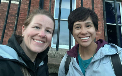 Two people smiling in front of a historic brick building in Belfast.