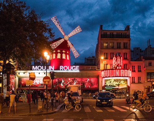 Esterno del Moulin Rouge di Parigi illuminato di notte con luci vivaci e l'iconico mulino a vento