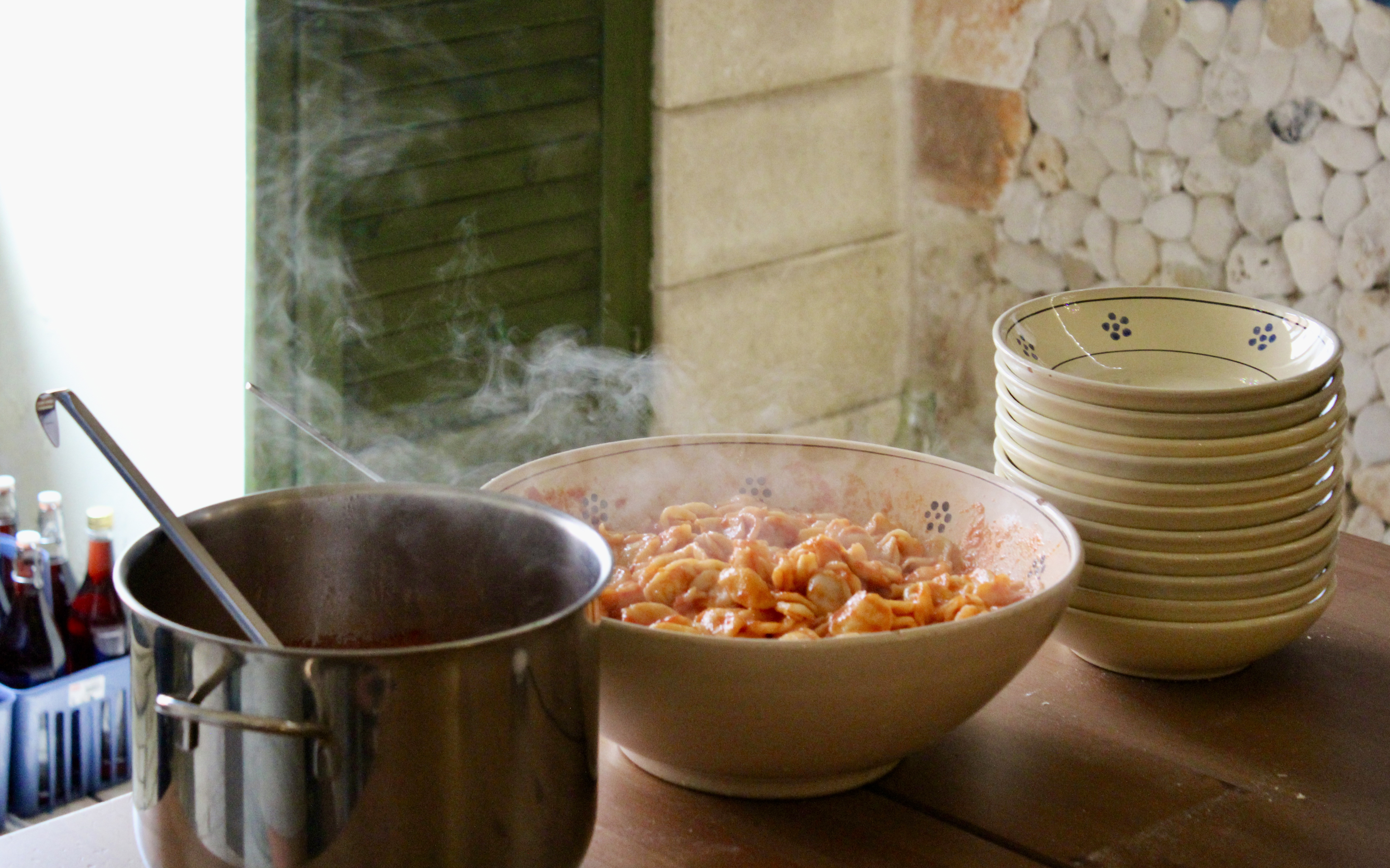 Steaming pasta in a bowl next to a pot during Polignano a Mare cooking class.