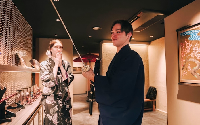 Tourists in traditional attire exploring Japanese swords in a cultural exhibit.