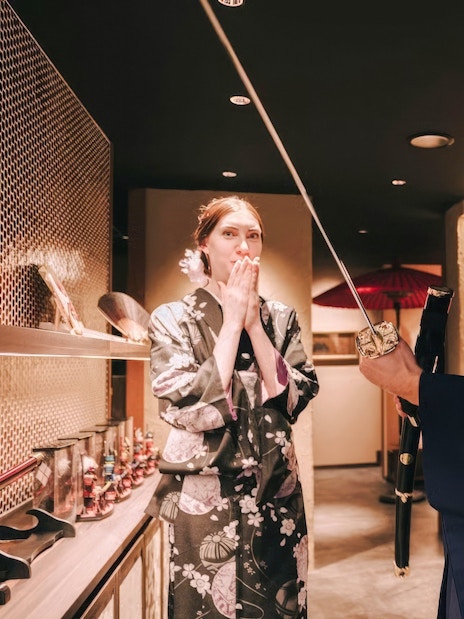 Tourists in traditional attire exploring Japanese swords in a cultural exhibit.