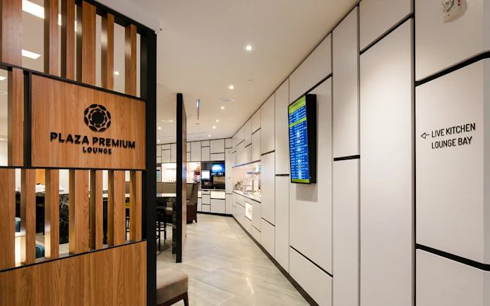 Plaza Premium Lounge entrance, Terminal 3, Toronto Pearson Airport, with seating and flight info display.