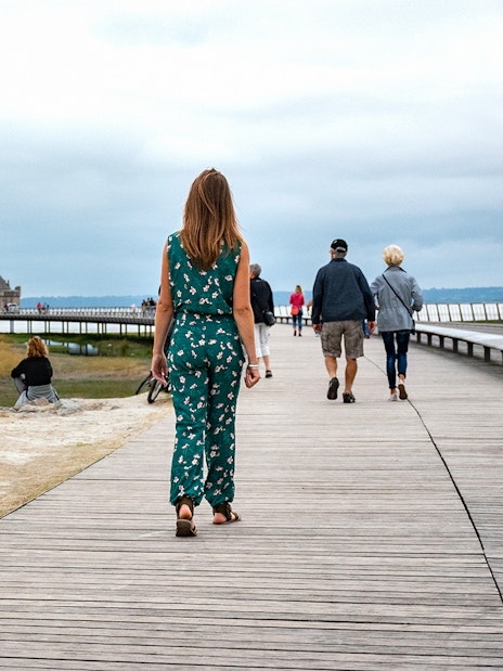 Visitors walking on a boardwalk towards Mont Saint-Michel in France.