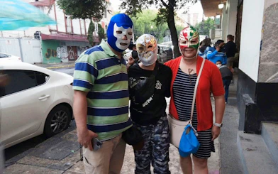 Three people wearing Lucha Libre masks outside Arena Mexico.