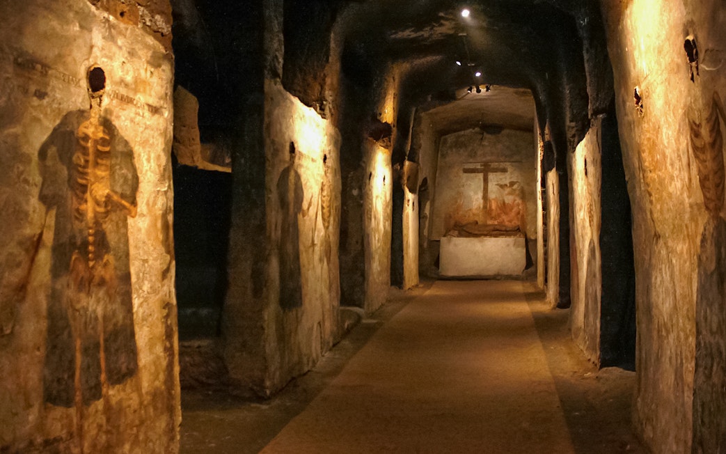 Catacombs of San Gaudioso corridor with ancient frescoes and burial niches.