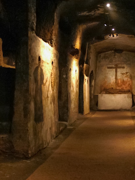Catacombs of San Gaudioso corridor with ancient frescoes and burial niches.