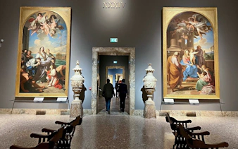 Visitors walking through the gallery at Pinacoteca di Brera, Milan, with classical paintings displayed.