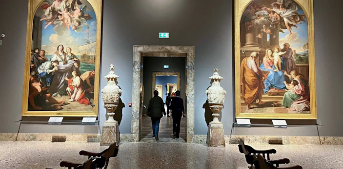 Visitors walking through the gallery at Pinacoteca di Brera, Milan, with classical paintings displayed.