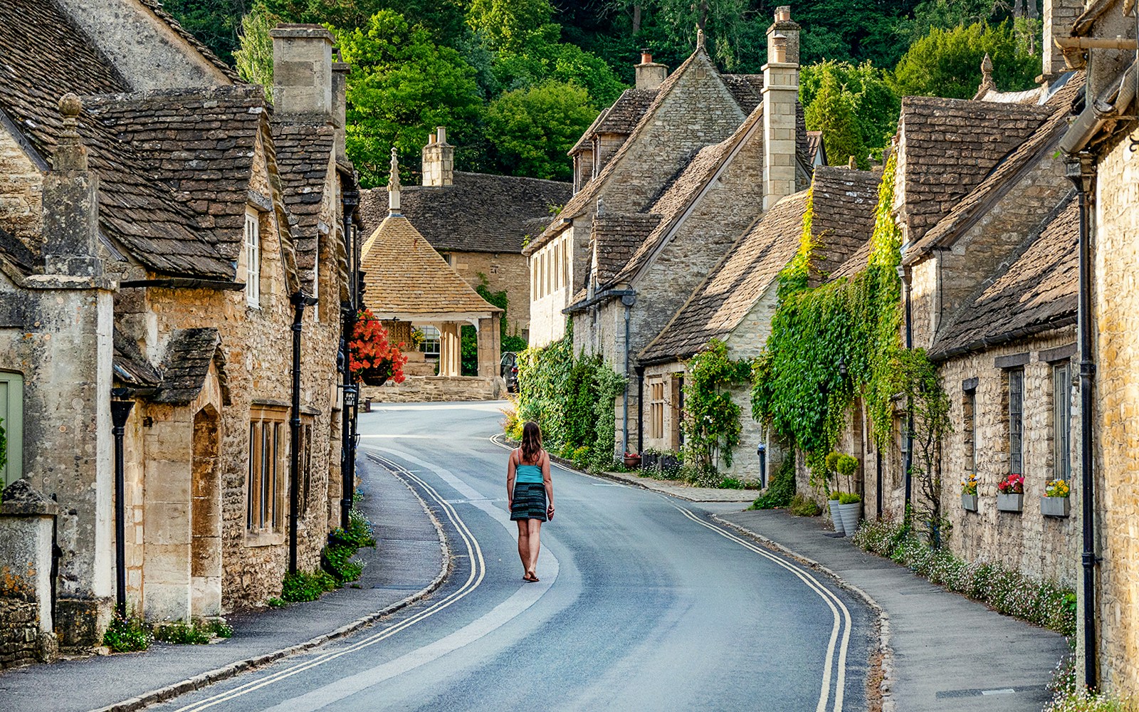 Cotswolds village street with stone cottages and a person walking, Oxford tour.