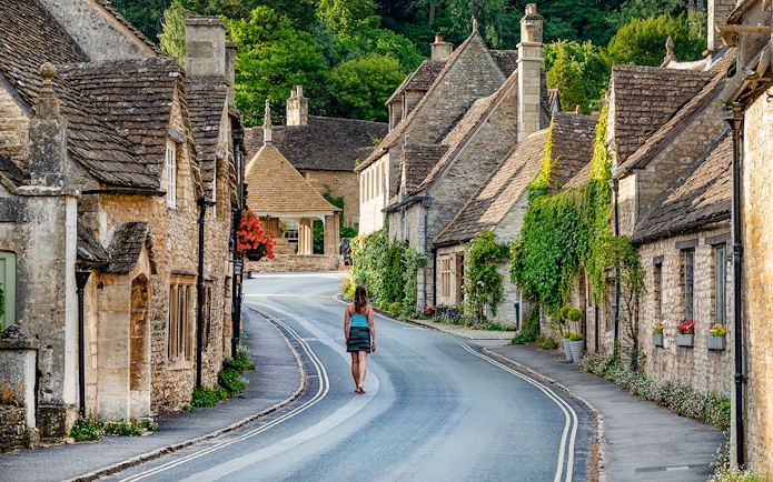 Cotswolds village street with stone cottages and a person walking, Oxford tour.