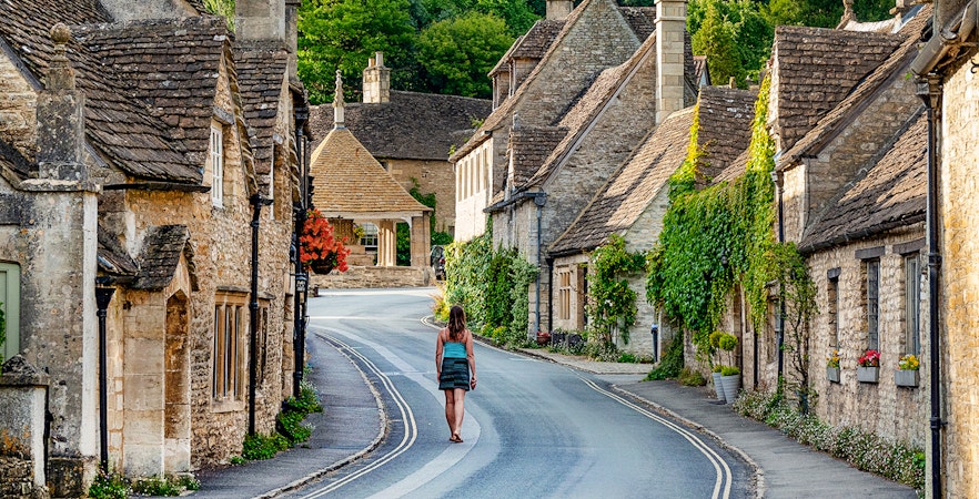 Cotswolds village street with stone cottages and a person walking, Oxford tour.