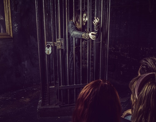 Witch in a cage performing for visitors at York Dungeon's Curse of the Witch attraction.