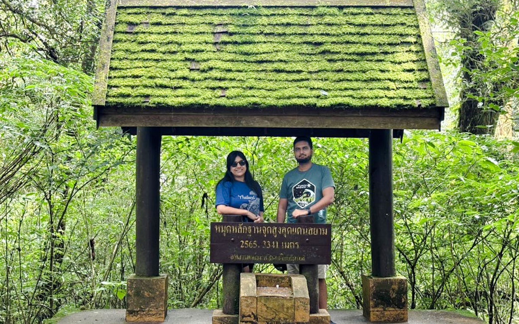 Visitors at a moss-covered sign in Doi Inthanon National Park, Chiang Mai.