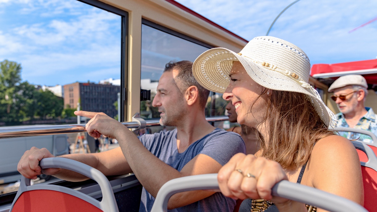 Hop-On Hop-Off bus with tourists passing Berlin landmarks.
