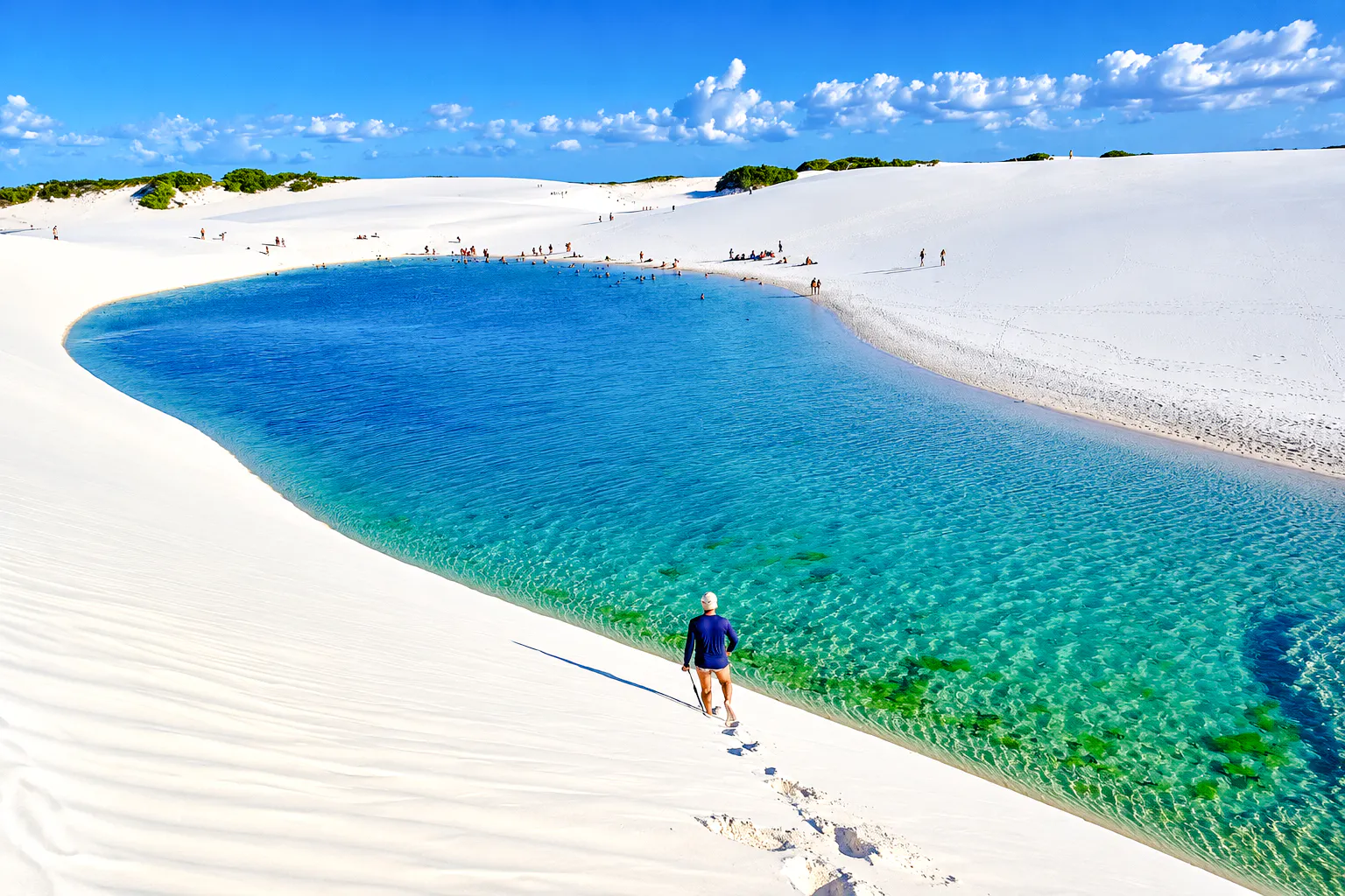 Tourist walking on white sand dunes by Lagoa Bonita, Barreirinhas, Brazil.