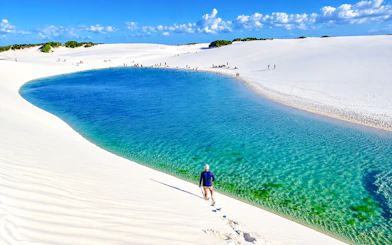Tourist walking on white sand dunes by Lagoa Bonita, Barreirinhas, Brazil.