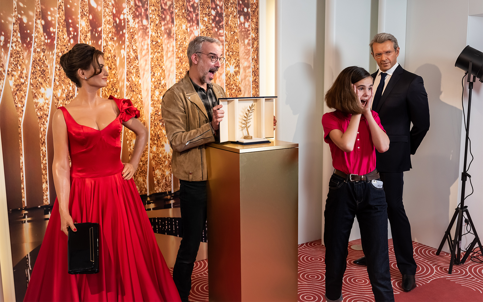 Grévin Wax Museum visitors admire wax figures and a Palme d'Or trophy display.
