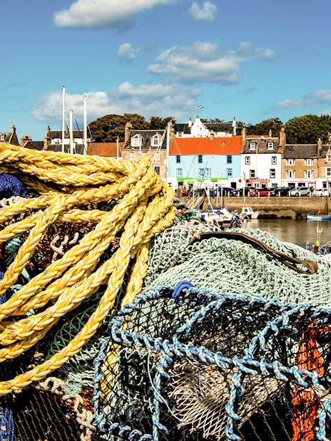 Fishing nets and colorful houses in a Fife village harbor, part of the St Andrews tour from Edinburgh.