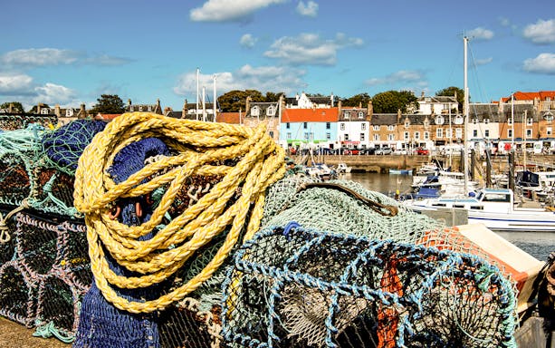 Fishing nets and colorful houses in a Fife village harbor, part of the St Andrews tour from Edinburgh.