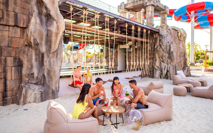 People enjoying drinks on a sandy beach at Andamanda Phuket.