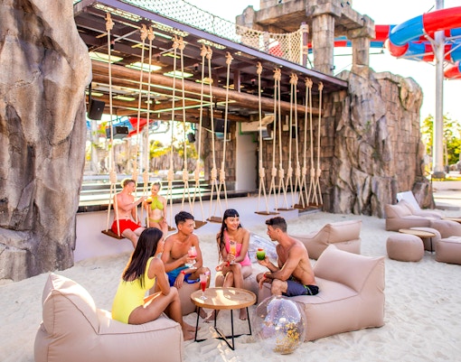 People enjoying drinks on a sandy beach at Andamanda Phuket.