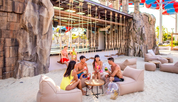 People enjoying drinks on a sandy beach at Andamanda Phuket.