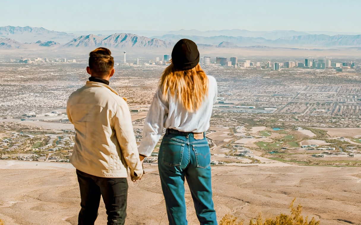 Couple holding hands on a hill overlooking Las Vegas and Red Rock Canyon, Nevada.
