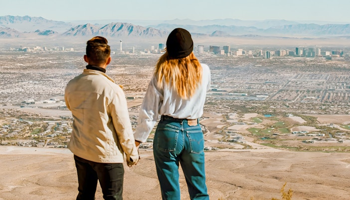 Couple holding hands on a hill overlooking Las Vegas and Red Rock Canyon, Nevada.