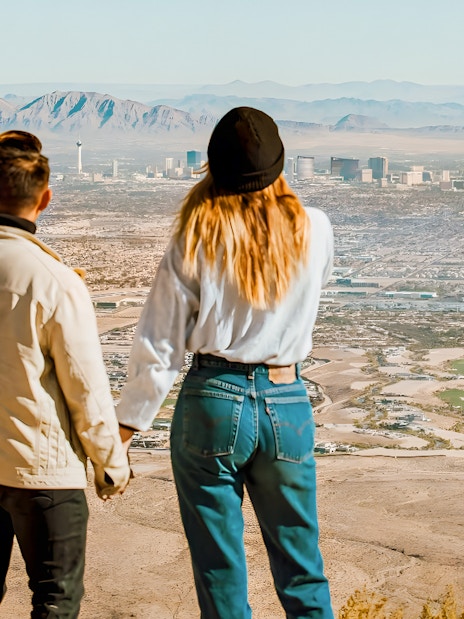 Couple holding hands on a hill overlooking Las Vegas and Red Rock Canyon, Nevada.