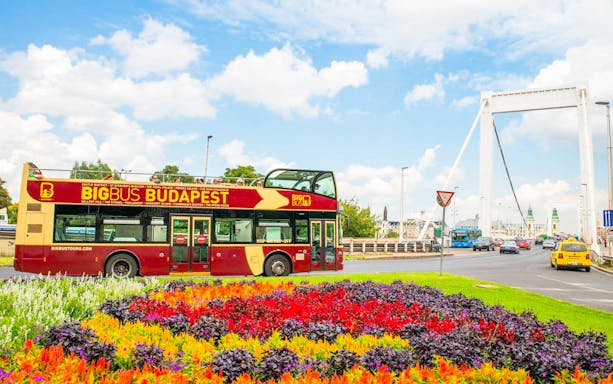 Budapest Big Bus near Elizabeth Bridge with colorful flowers in foreground.