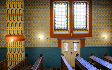 Interior view of Kazinczy Synagogue in Budapest with colorful stained glass windows.