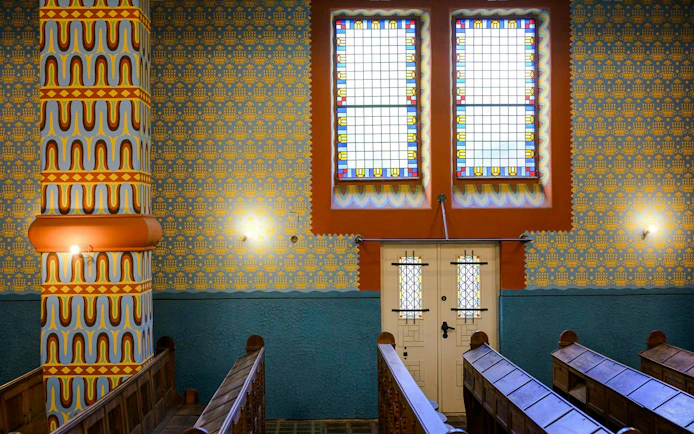 Interior view of Kazinczy Synagogue in Budapest with colorful stained glass windows.