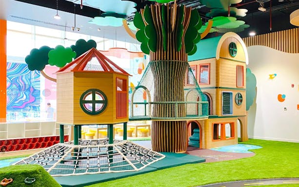 Indoor play area with climbing nets and treehouse at Orange Wheels, Global Village, Dubai.