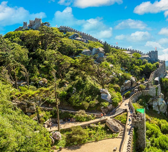 Moorish Castle in Lisbon with stone walls and lush greenery.